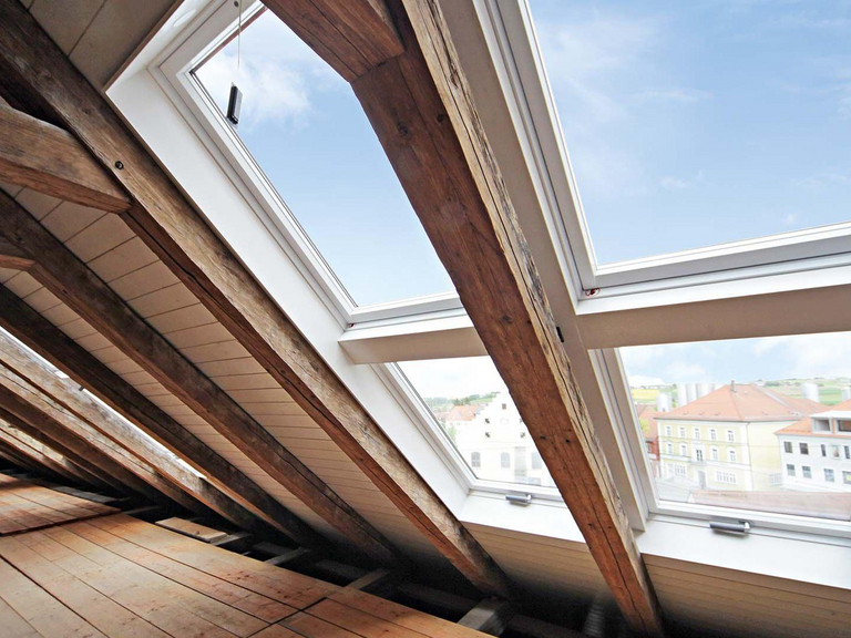 Dachgeschoss mit alten Holzbalken und mehreren Dachfenstern 